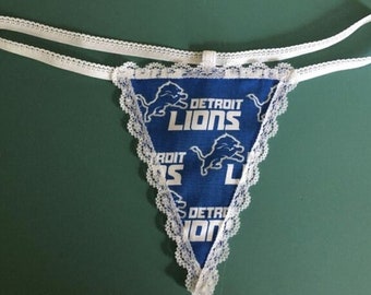 May include: White lace trim with a blue triangle fabric panel featuring the Detroit Lions logo and repeated images of a lion. The fabric is blue with white text and images.