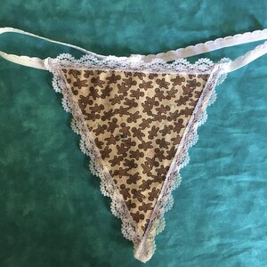 May include: White lace trim lingerie with a brown gingerbread man print.