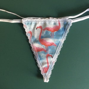 May include: White lace trim lingerie with a blue and pink flamingo print.
