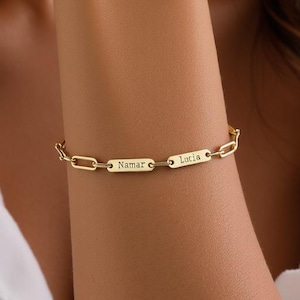 May include: Gold chain bracelet with two personalised name tags. The tags read "Namar" and "Lucia".