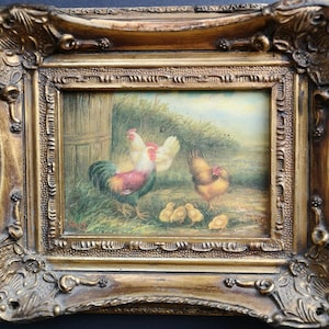Puede incluir: Pintura enmarcada que representa un gallo, una gallina y polluelos en una escena de granja. El gallo tiene plumas rojas, blancas y verdes. La pintura está en un marco dorado ornamentado.