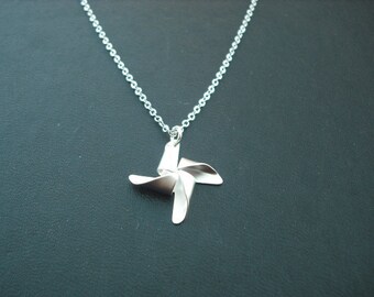 May include: A silver necklace with a silver pinwheel pendant.