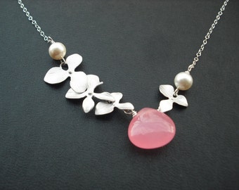 May include: A silver necklace with a pink stone pendant and silver flower charms. The necklace also features two white pearl accents.