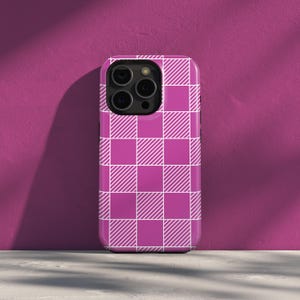 May include: A magenta and white checkered phone case. The case features a repeating pattern of magenta squares with white diagonal stripes, creating a gingham effect. The phone case is shown against a magenta background.