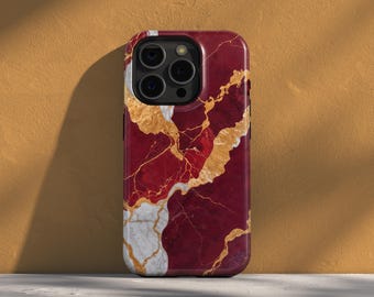 May include: A smartphone case with a striking marble design. The case features a deep red base color with gold and white veining, creating a luxurious aesthetic. The case has a glossy finish and a camera cutout.