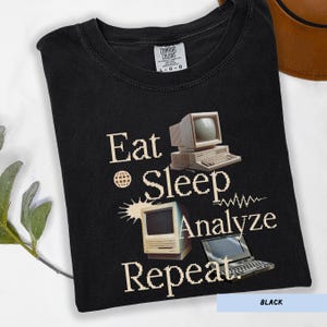 May include: Black t-shirt with the words "Eat Sleep Analyze Repeat" and images of vintage computers. The shirt also features a small Comfort Colors tag.