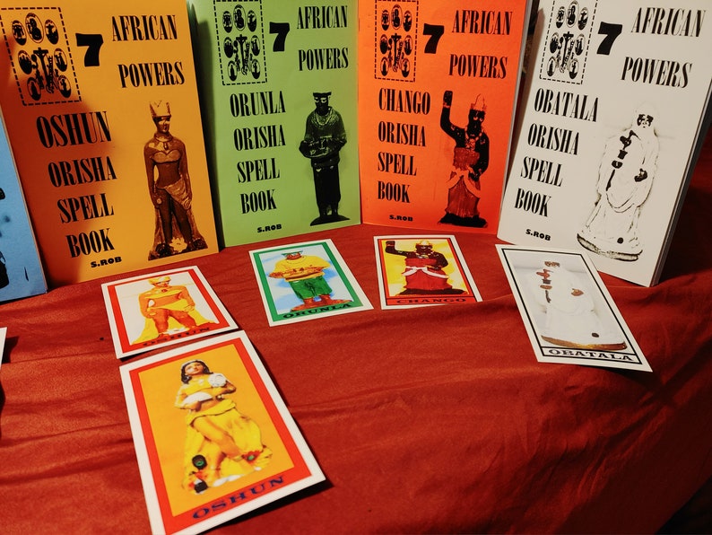 Pode incluir: Sete livros coloridos intitulados "African Powers" com os nomes de diferentes divindades Orisha na capa. Cada livro tem uma imagem do Orisha. H&aacute; tamb&eacute;m sete cartas com imagens do Orisha.