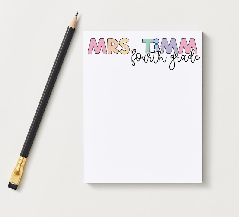 May include: A rectangular notepad with white paper featuring the text MRS. TIMM in colourful pastel block letters and the words fourth grade in black cursive script below it, accompanied by a black wooden pencil with a gold ferrule and eraser.