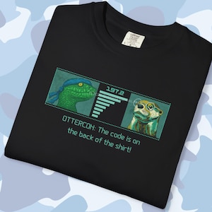 May include: Black t-shirt with a graphic featuring a green reptile and an otter, both with accessories, and the text "OTTERCON: The code is on the back of the shirt!". The shirt has a tag in the upper right corner.
