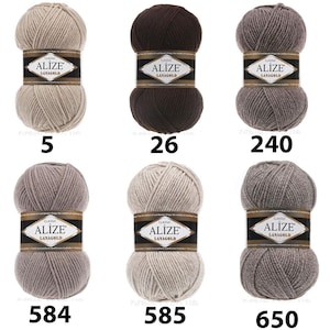 May include: Six balls of Alize Lanagold yarn in a range of neutral shades. The balls are numbered 5, 26, 240, 584, 585, and 650. Each ball has a black and gold label.