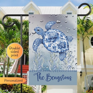 May include: A blue and white garden flag with a blue and white floral patterned sea turtle swimming in a blue and white water background. The text "The Bengstons" is at the bottom of the flag.