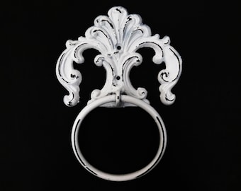 May include: White cast iron towel ring with a decorative, ornate design. The ring is attached to a wall mount with a scroll-like design.