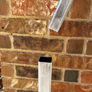 May include: Close-up of two pieces of metal pipe, one is cut and the other is whole. Both are painted white with a textured finish.