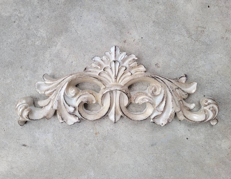 May include: White painted ornate decorative wall decor with a floral design.