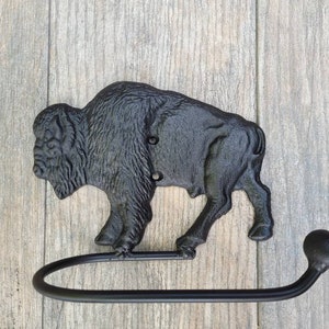 May include: Black cast iron buffalo toilet paper holder with a black metal arm. The buffalo is in a walking pose.