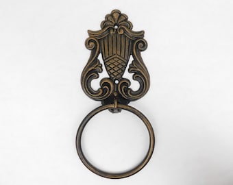May include: Ornate gold and black metal towel ring with a decorative scroll design.