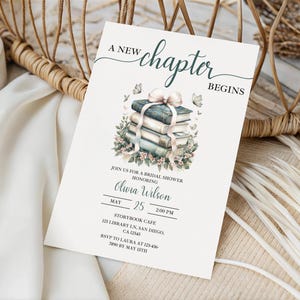 May include: A bridal shower invitation with the text "A New Chapter Begins." The invitation features a watercolor illustration of a stack of books tied with a ribbon and floral accents. The invitation includes the name Olivia Wilson, the date May 25, and the time 2:00 PM.