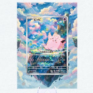 Peut inclure: Une carte à collectionner Pokémon encadrée représentant un personnage Clefairy rose. La carte comporte du texte japonais et un arrière-plan coloré avec des nuages et des îles flottantes. La carte est présentée sur un support transparent.