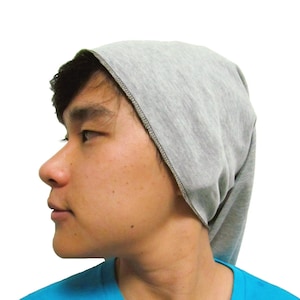 May include: A person wearing a gray cotton bandana tied around their head and a blue t-shirt.