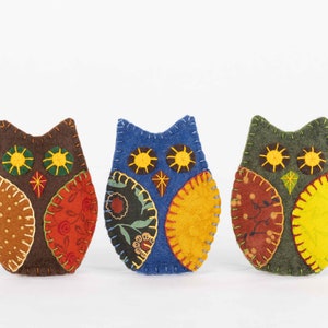 Embroidered felt owls with patterned wings in autumnal colours.