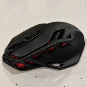 May include: A black computer mouse with a red, honeycomb-like design. The mouse has a scroll wheel and two buttons.