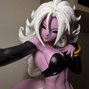 May include: A collectible figure of a character with light purple skin, long white hair, and red eyes. The figure wears a black top, black arm sleeves, and gold wrist cuffs. A thick, curved purple tail extends from the lower back area of the figure.