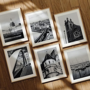 May include: A white ceramic mug with a black handle and the text "But First, Coffee" in a bold, black font. The mug is set against a blurred background, suggesting a cozy setting. The mug appears to be approximately 4 inches tall.