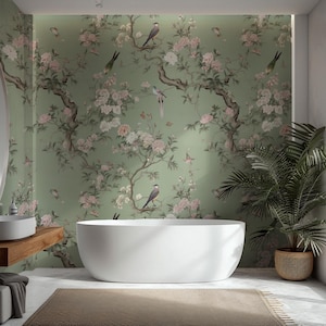 Könnte beinhalten: Ein modernes Badezimmer mit einer weißen Badewanne, einem Holzwaschtisch mit einem weißen Waschbecken und einem großen ovalen Spiegel. Die Wände sind mit einer grünen Blumentapete mit Vögeln und Blumen geschmückt. Eine Topfpflanze und ein Teppich vervollständigen den Raum.