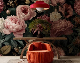 Puede incluir: Una escena de diseño de interiores con un vibrante papel pintado floral con grandes flores rosas y burdeos. Una silla redonda de terciopelo naranja con un cojín a juego se encuentra frente a una mesa de madera. Una lámpara colgante roja cuelga encima.