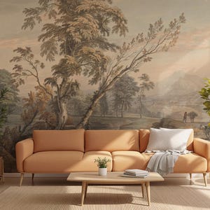 May include: A living room with a tan sofa, a light-coloured throw pillow, and a grey blanket. A landscape mural is on the wall behind the sofa. Two potted plants flank the sofa, and a small wooden table sits in front.