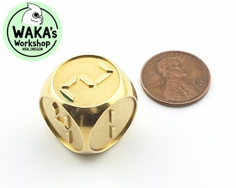 May include: A gold metal dice with a unique design. The dice is about the size of a US penny.