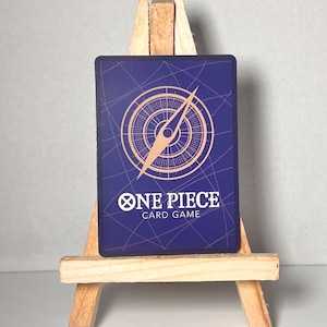 May include: A blue card with a compass design and the text "ONE PIECE CARD GAME" in gold lettering.
