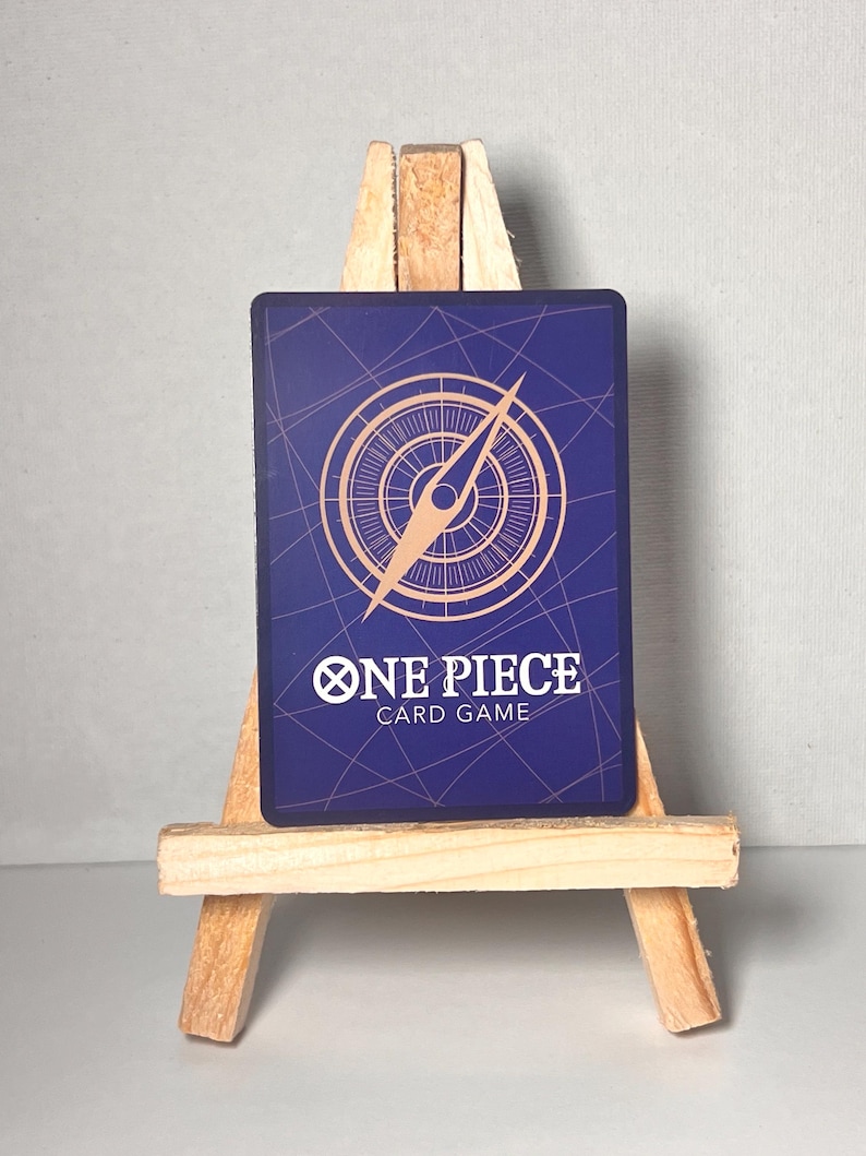 May include: A blue card with a compass design and the text "ONE PIECE CARD GAME" in gold lettering.