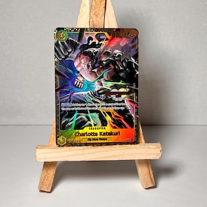 May include: A gold foil trading card featuring a character from the anime One Piece. The character is Charlotte Katakuri, a powerful pirate with a mohawk and a scar over his eye. The card has a holographic effect and is in excellent condition.