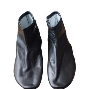 Può includere: Un paio di stivaletti in pelle nera con punta a punta e cerniera laterale.