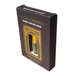 May include: A brown box with gold accents and a small clear glass bottle with a gold cap. The box has the text "MAKAM-I İBRAHİM" and "ORJİNAL ALKOLS&Uuml;Z ESANS" in gold lettering. The box also has the text "عطر مقام ابراهیزم" in Arabic script.