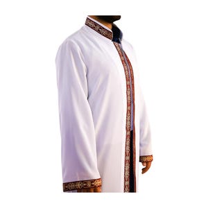 May include: White robe with ornate red and gold trim along the edges and down the front. The robe has a mandarin collar and long sleeves. The trim features a detailed floral pattern. The robe is worn over a dark blue garment.