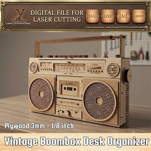 Puede incluir: Un organizador de escritorio con forma de boombox cortado a láser en madera contrachapada de 3 mm. El diseño incluye un asa, dos altavoces circulares con patrón de panal, una platina de casete, una pantalla de radio y varios botones.
