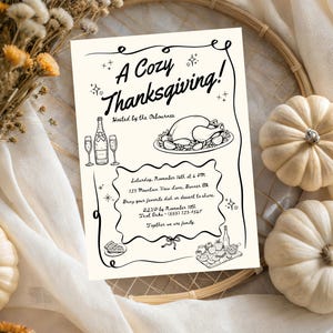 May include: A cream-coloured Thanksgiving invitation with black text and illustrations, including a turkey, champagne, and pumpkins. The text reads "A Cozy Thanksgiving!" and includes event details. Dried flowers and small pumpkins surround the invitation.