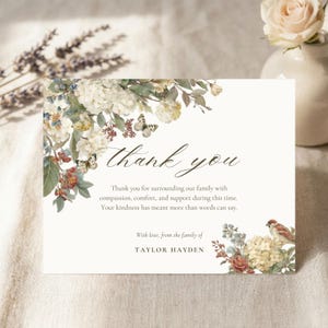 May include: A cream-colored thank you card with floral and butterfly illustrations. The card features the words "thank you" in elegant script and a message of gratitude. The family name "TAYLOR HAYDEN" is also printed on the card.