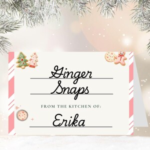 May include: A festive card with the words "Ginger Snaps" in elegant script, with the text "From the kitchen of: Erika" below. The card features pink and white striped accents and gingerbread cookie illustrations, perfect for the holiday season.