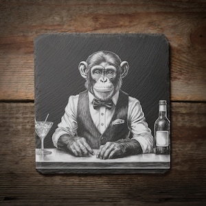 Peut inclure: Illustration en noir et blanc d'un chimpanzé en gilet et nœud papillon, derrière un bar. Un cocktail et une bouteille sont sur le bar. L'image est sur un dessous de verre carré en ardoise gris foncé, avec un fond en bois.