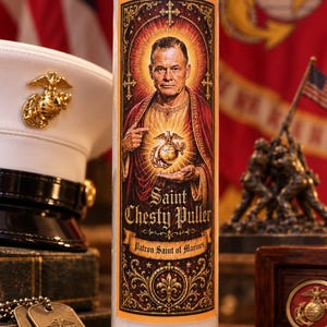 May include: A tall cylindrical white wax candle in a clear glass jar featuring a label with an illustration of Chesty Puller in a red robe, holding a Marine Corps emblem. The text reads Saint Chesty Puller and Patron Saint of Marines.