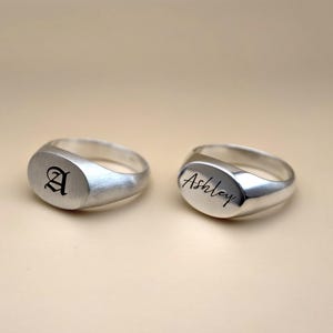 Puede incluir: Dos anillos de sello de plata. Un anillo est&aacute; grabado con la letra "A" en fuente g&oacute;tica. El otro anillo est&aacute; grabado con el nombre "Ashley" en cursiva.