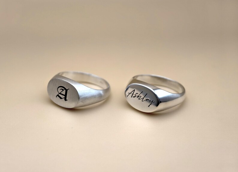 Puede incluir: Dos anillos de sello de plata. Un anillo est&aacute; grabado con la letra "A" en fuente g&oacute;tica. El otro anillo est&aacute; grabado con el nombre "Ashley" en cursiva.