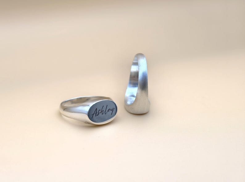 Puede incluir: Dos anillos de sello de plata, uno con el nombre "Ashley" grabado en la parte superior.