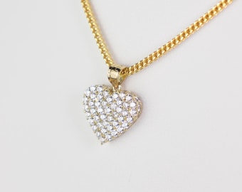 May include: A gold chain necklace with a heart-shaped pendant encrusted with clear cubic zirconia stones.