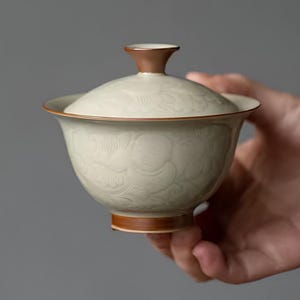 May include: A set of three ceramic mugs with a speckled, matte finish. The mugs are in shades of cream, light gray, and dark gray. Each mug has a simple, minimalist design, perfect for coffee or tea.