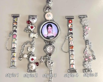 May include: A collection of five decorative watch bands and a smartwatch. The bands are silver-toned and adorned with charms, including hearts, bows, and small images. The smartwatch displays a photo of a person on its screen.