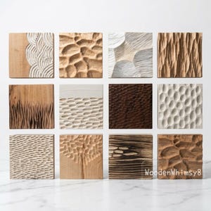 May include: A collection of twelve square wooden tiles, each with a unique carved texture. The designs include organic patterns, linear grooves, and textured surfaces. The colour palette features natural wood tones, white, and brown.